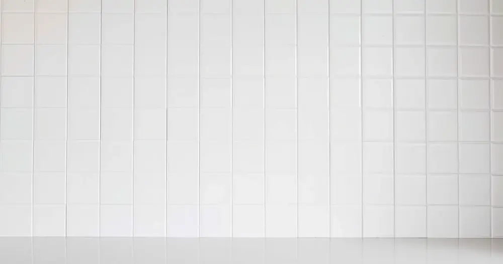 Parede revestida de azulejos brancos em uma cozinha clara e organizada
