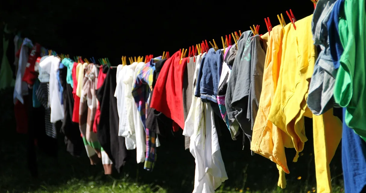 Roupas coloridas penduradas em um varal, ilustrando como tirar mancha de mofo em roupas