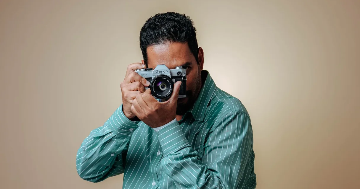 Fotógrafo segurando uma câmera diante do rosto